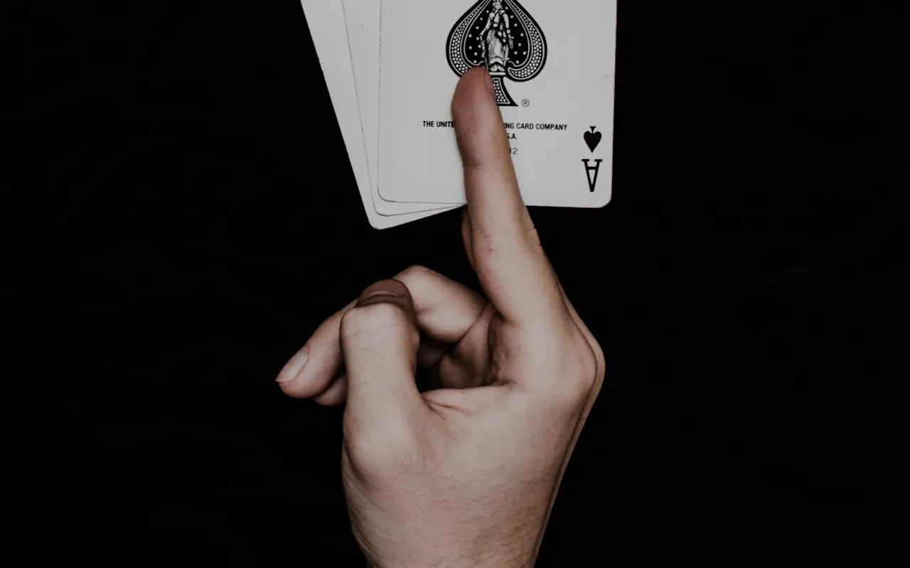 Hand holding up the ace of spades against a black background