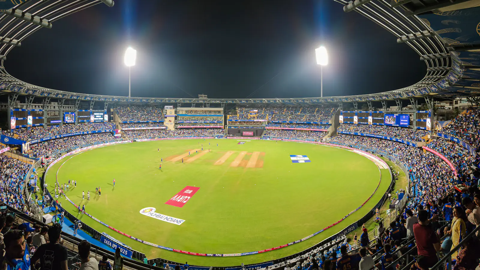 Floodlit cricket stadium packed with fans at night