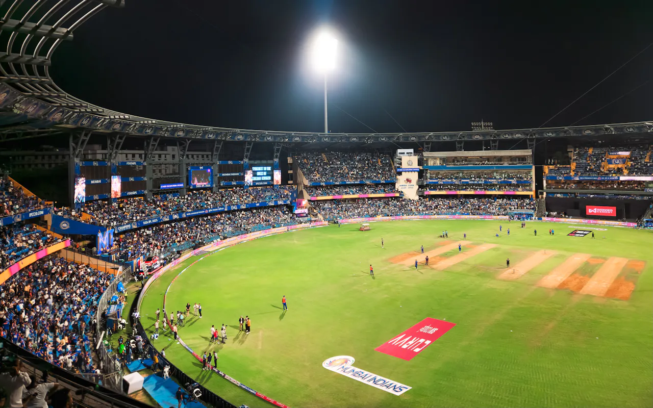 Packed cricket stadium at night under floodlights