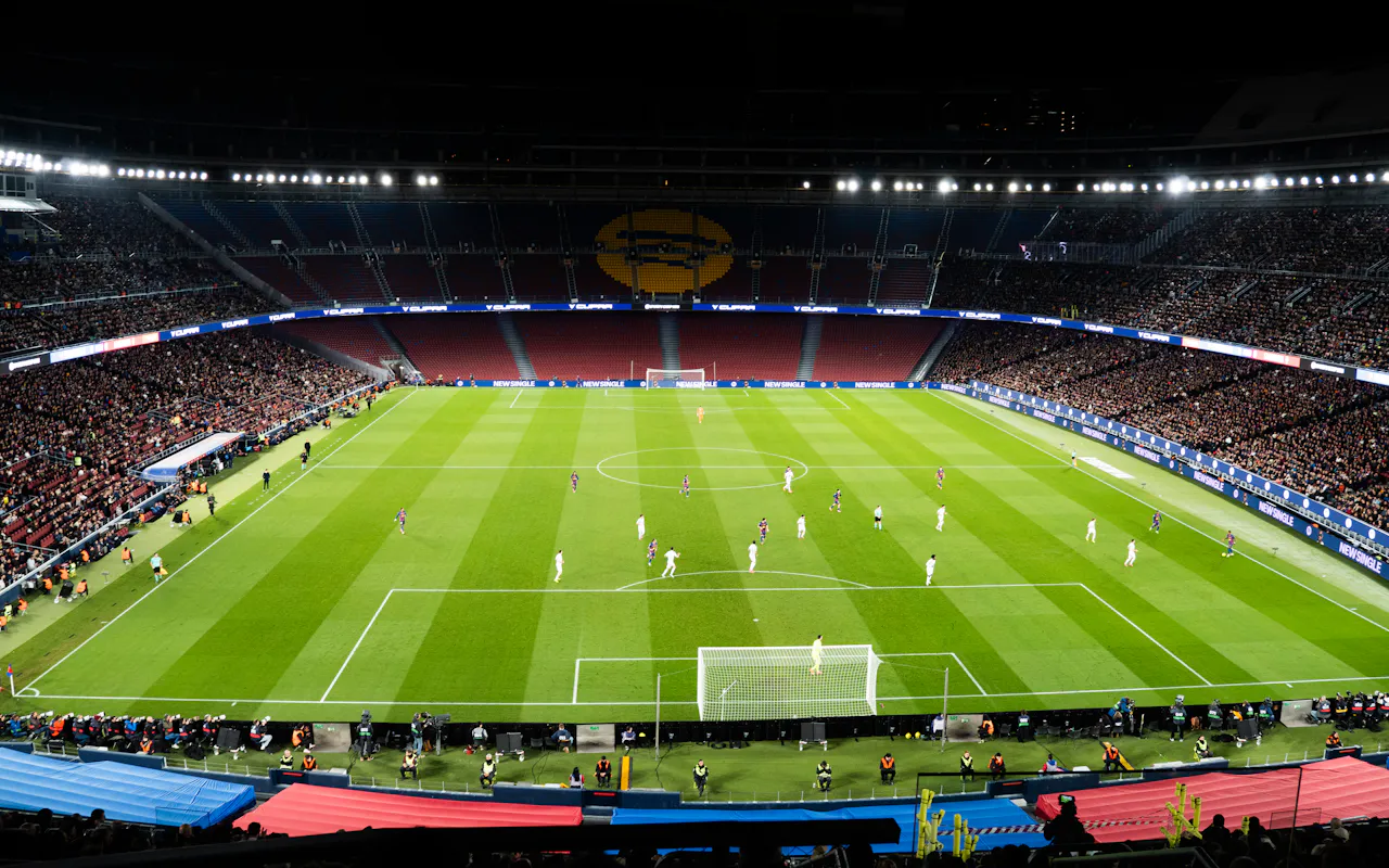 Floodlit football stadium at night with a match in progress