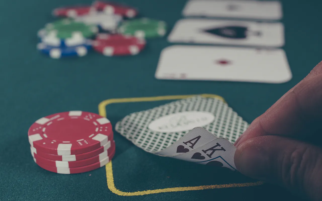 Poker table with an ace and king in hand beside stacks of casino chips